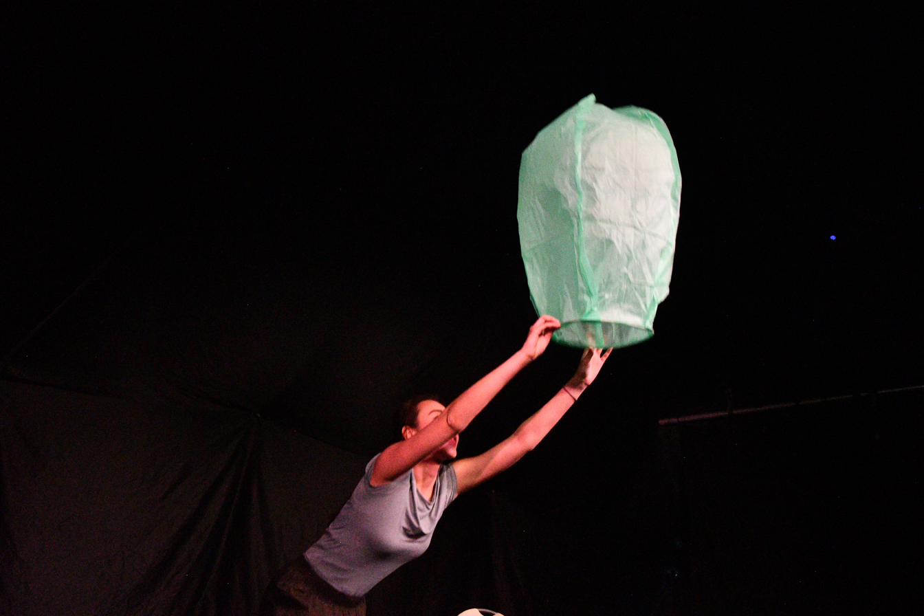 A performer leans forward, listening, in low warm light.