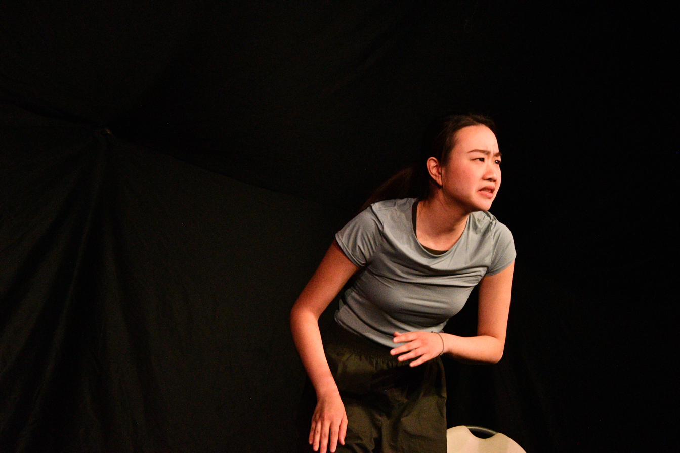A performer cradles a glass jar close, lit in warm amber.