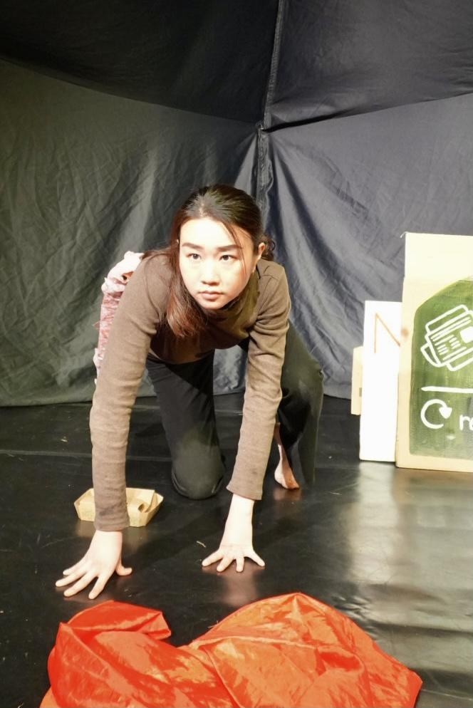 A performer crawls low across the stage, mid-movement.