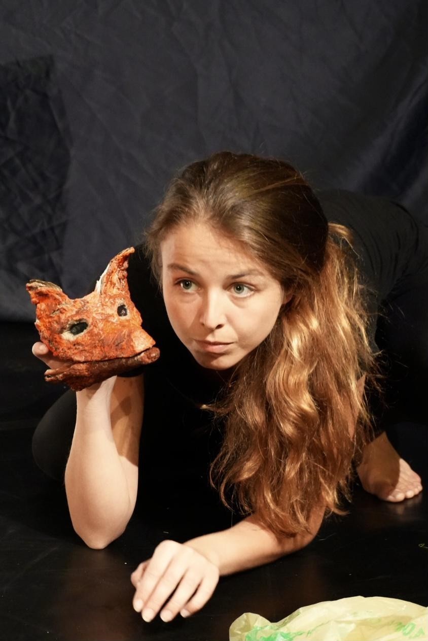 A performer wearing a fox mask, poised and watchful.