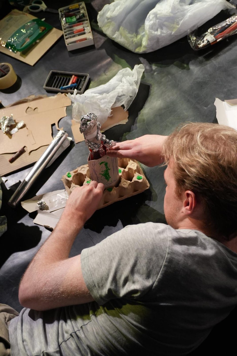 A participant builds a figure from an egg carton and foil.
